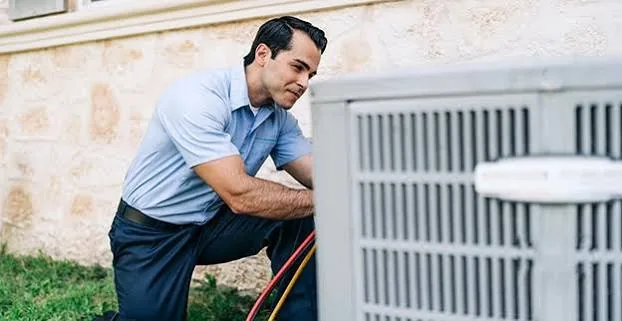 HVAC technician repairing an outdoor air conditioning unit